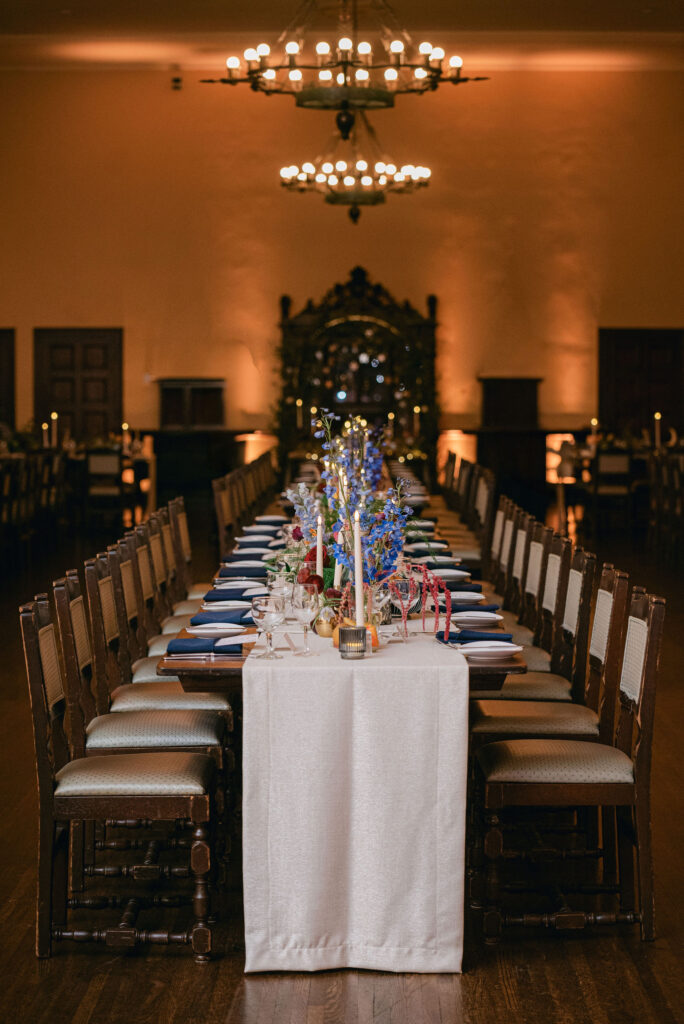 Moody reception lighting with chandeliers and floral centerpieces