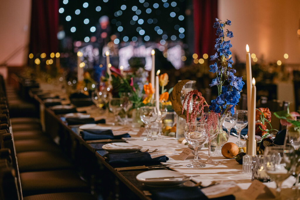 Moody reception lighting with chandeliers and floral centerpieces