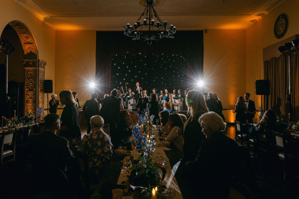 Moody reception lighting with chandeliers and floral centerpieces